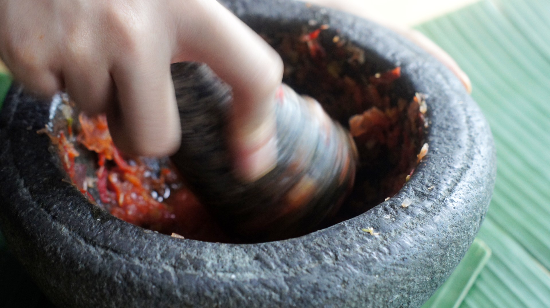 Pounding the <em>rempah</em> in the <em>batu lesung</em>. April 2020, photo by Wai Zi Ying.